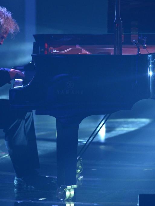 Der Pianist Joachim Kühn spielt auf einer blau erleuchtenden Bühne an einem Flügel.