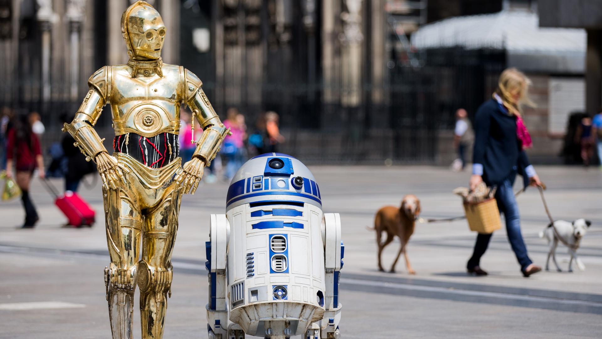 Die Roboter "C-3PO" (l) und R2-D2 aus den Star-Wars-Filmen als Wachsfiguren vor dem Kölner Dom.