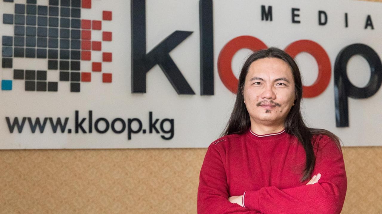 Kloop-Gründer Bektour Iskender posiert vor seinem Firmenlogo.
