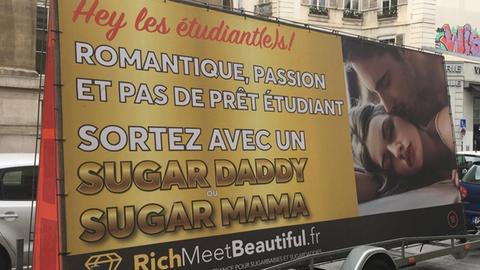 An advertising board of the dating site "RichMeetBeautiful" reading "students, romantic, passion and no student loan, meet a Sugar Daddy or a Sugar Mama" is displayed in a street of Paris on October 25, 2017. The advertising truck lauding a dating site near Paris universities and accused of inciting to "prostitution" by the city, was seized for "unauthorised display", said the Paris police prefecture on October 26, 2017