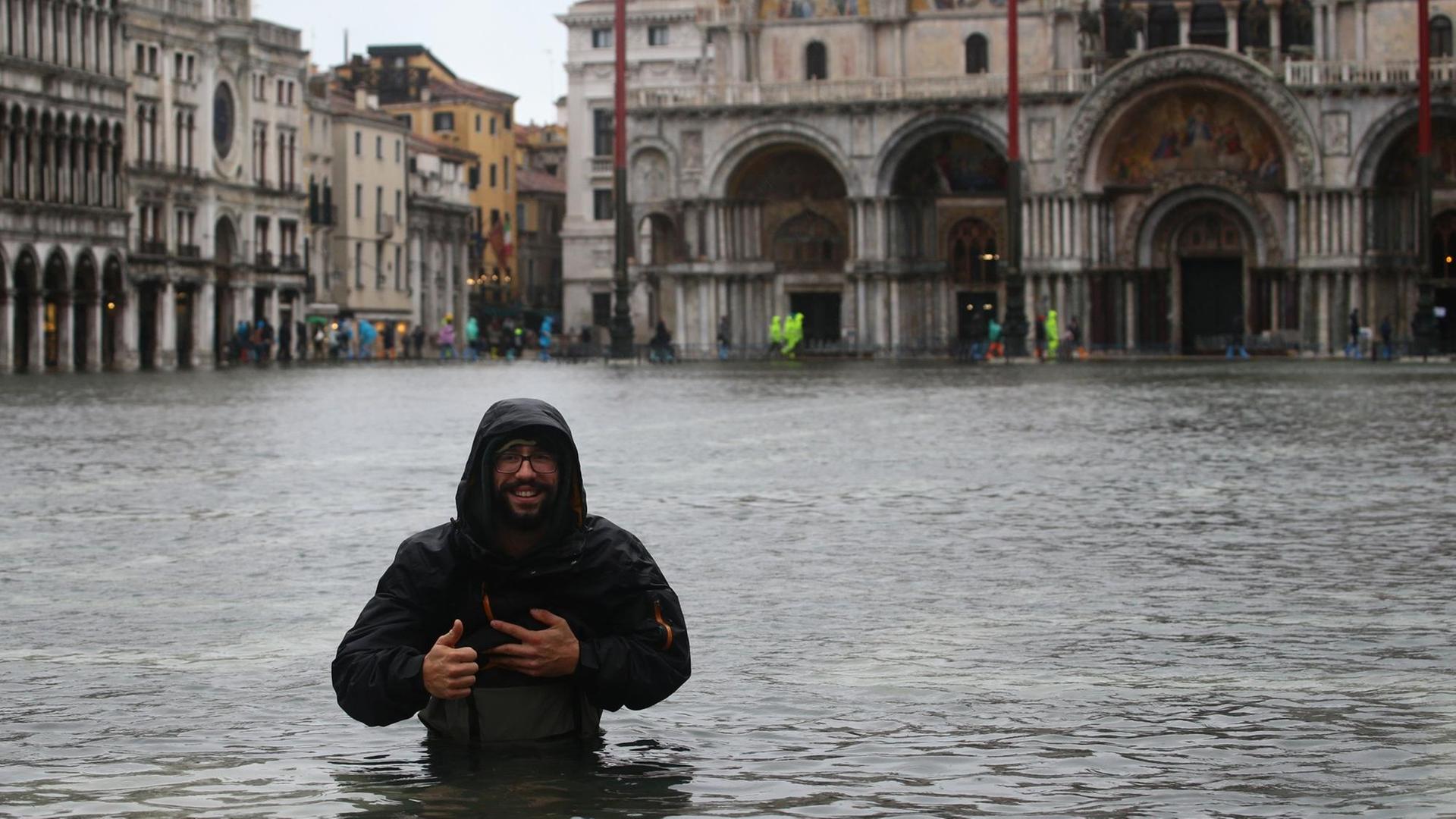 Ein Mann steht in Venedig bis zur Hüfte im Hochwasser.