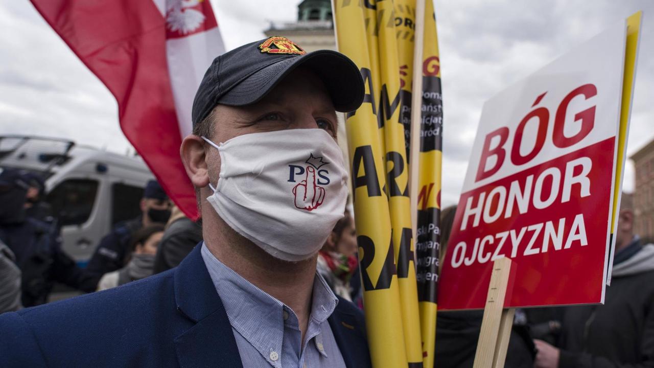 Demonstrant in Warschau bei Protest gegen Corona-Beschränkungen in Polen. Auf seinem Mundschutz steht ein kritischen Statement gegen die Regierungspartei PiS.