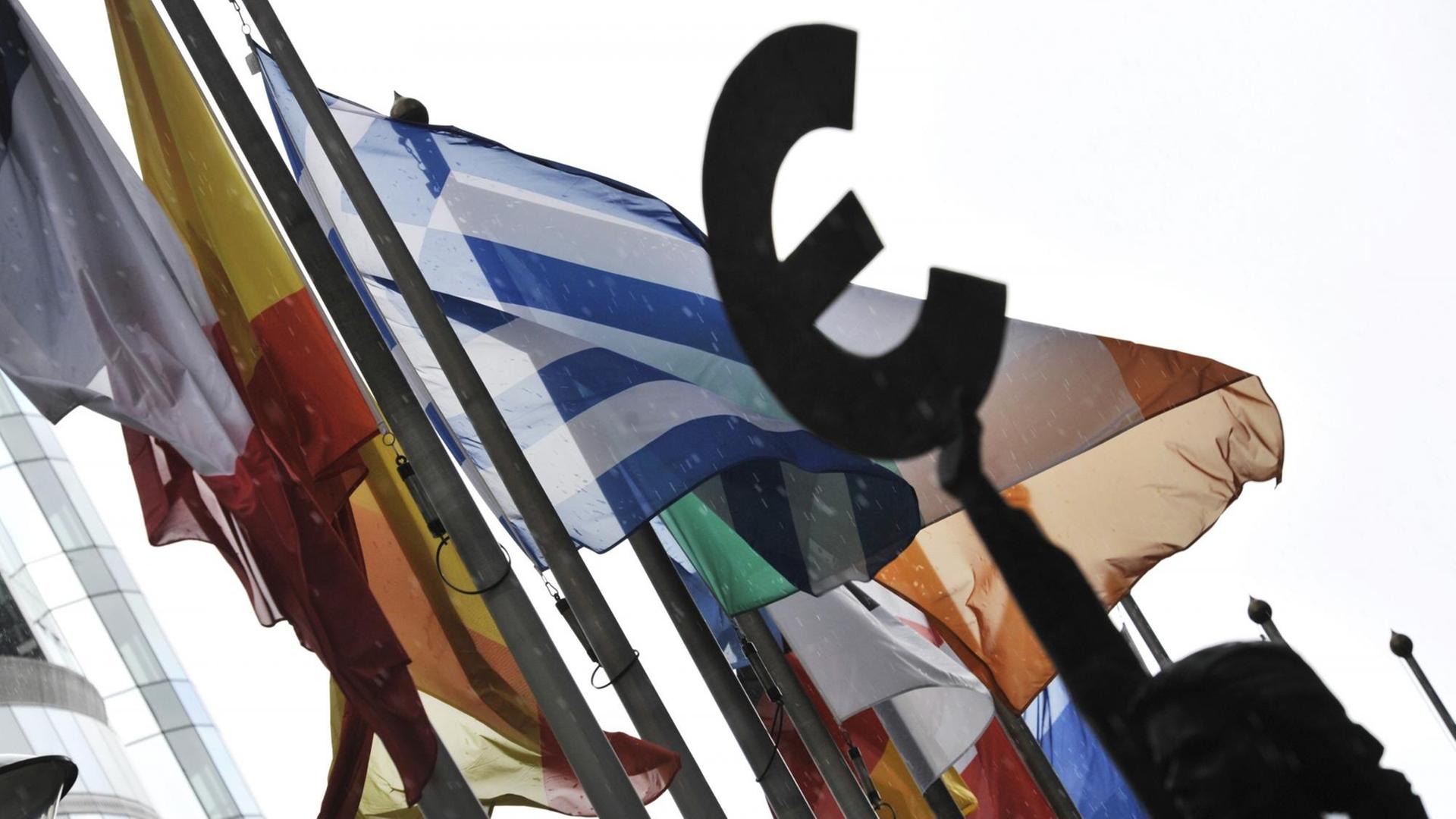Flaggen vor dem EU-Parlament in Brüssel, davor eine Frauen-Statue, die das Eurozeichen in der Hand hält