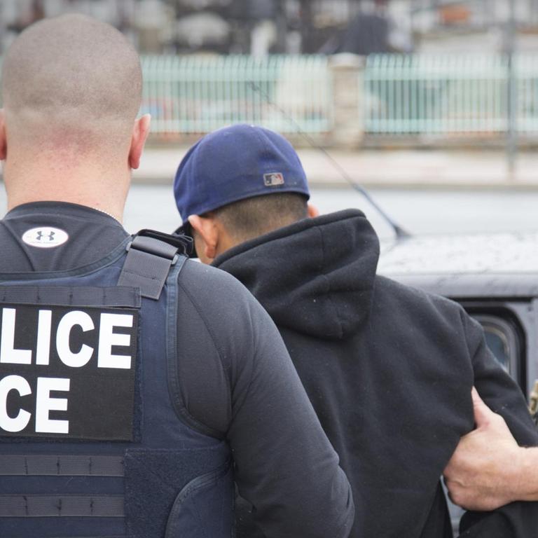 Mitarbeiter der US-Zollbehörde nehmen einen jungen Ausländer fest.