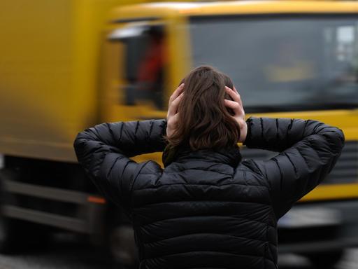 Eine Frau hält sich in Hamburg vor einem nahenden LKW die Ohren zu.