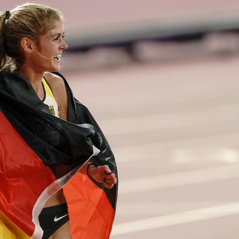 Die Drittplatzierte Konstanze Klosterhalfen aus Deutschland läuft mit einer deutschen Fahne eine Ehrenrunde bei der WM in Doha
