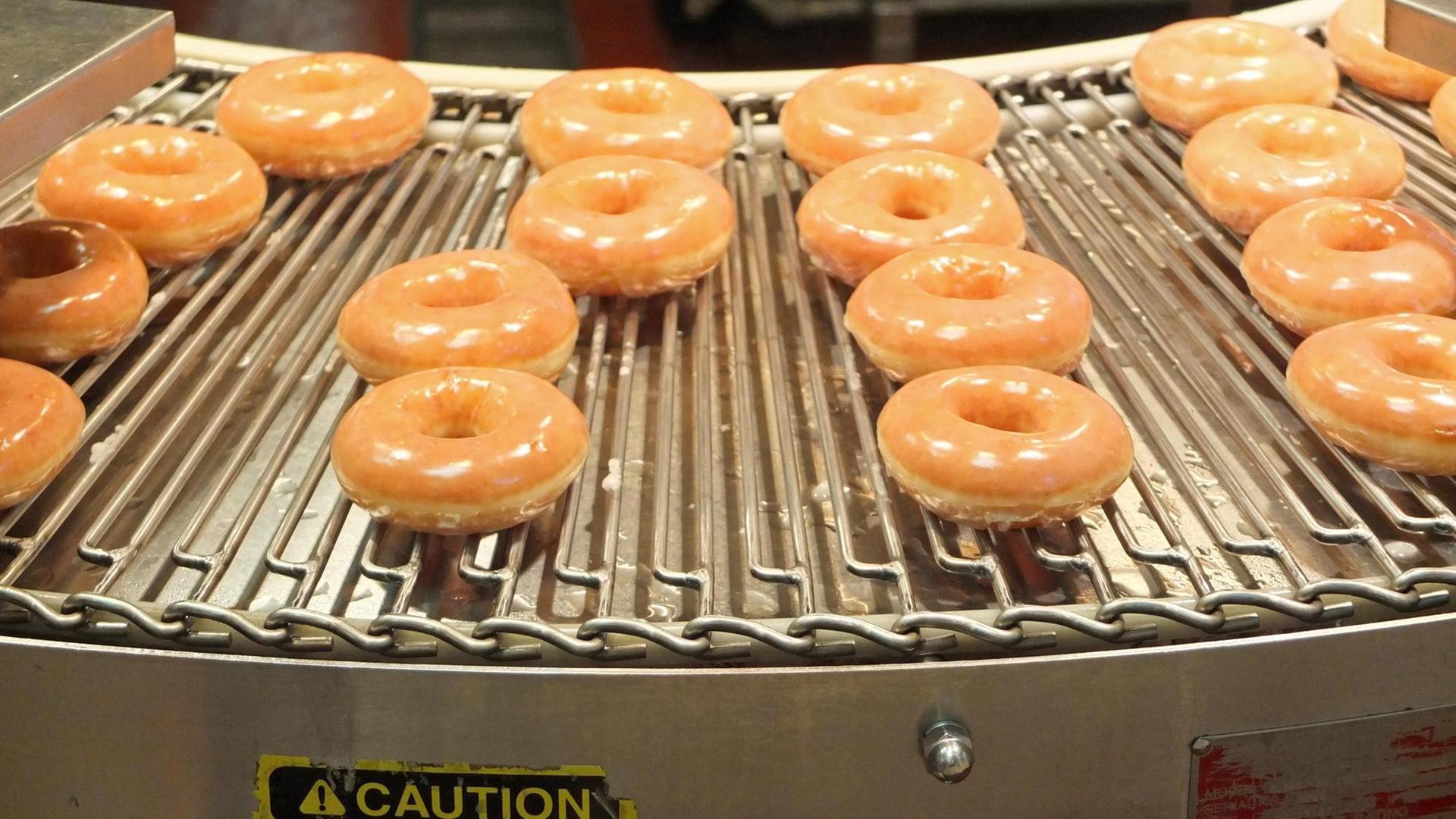 Mehrere Donuts liegen auf einem Blech. 