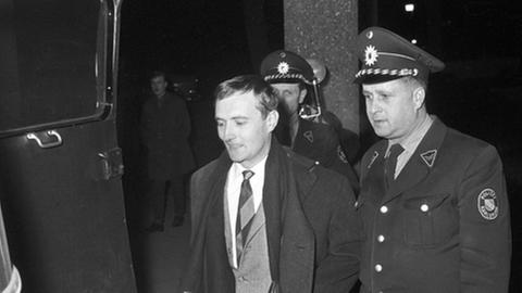 Spiegel-Herausgeber Rudolf Augstein wird am 08.01.1963 nach dem dritten Haftprüfungstermin von zwei Polizeibeamten aus dem Gebäude des Bundesgerichtshofes in Karlsruhe geführt.