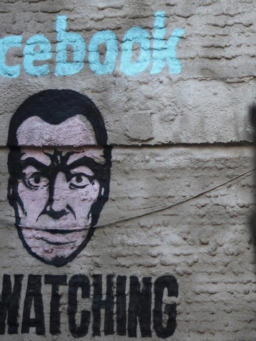 Ein Wandbild an einer Hauswand im Stadtteil Lavapiés von Madrid zeigt ein Gesicht und die Aufschrift "Facebook is watching".