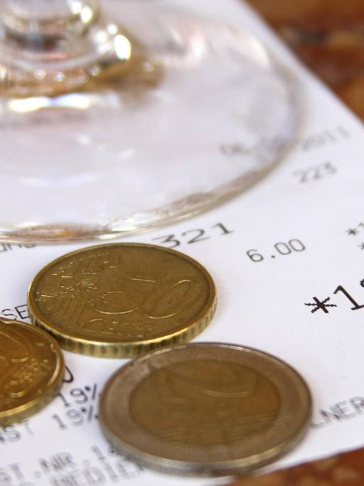 Quittung eines gastronomischen Betriebs mit Glas und Betrag in Euro und Münzen als Trinkgeld