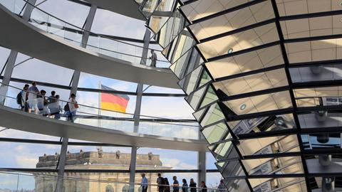 Blick von innen durch die Glaskuppel des Reichstages in Berlin. Davor weht die deutsche Flagge.