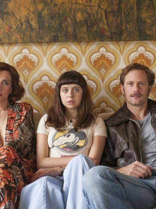 Kristen Wiig als Charlotte Goetze, Bel Powley als Minnie Goetze und Alexander Skarsgard als Monroe sitzen in einer Szene des Films "The Diary of a Teenage Girl" nebeneinander auf einem Sofa.