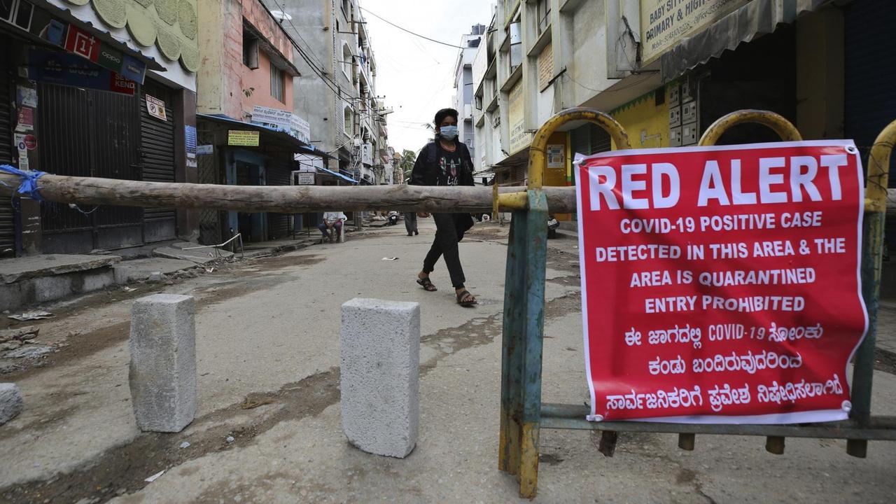 Ein Junge geht mit Mundschutz auf einer Straße, die von den indischen Behörden aufgrund der Corona-Pandemie gesperrt wurde. 