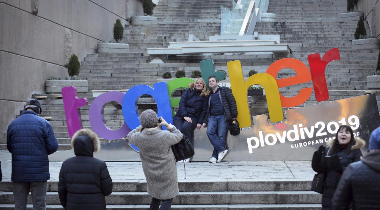 Zwei Menschen lassen sich vor einem bunten Schild mit der Aufschrift "together" fotografieren, mit der die bulgarische Stadt Plowdiw für ihren Titel als europäische Kulturhauptstadt 2019 wirbt. 

