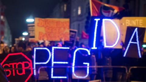 Gegner der Anti-Islam-Bewegung "Dügida" demonstrieren am 12.01.2015 in Düsseldorf (Nordrhein-Westfalen) mit einer Leuchtschrift "Stop PEGIDA"