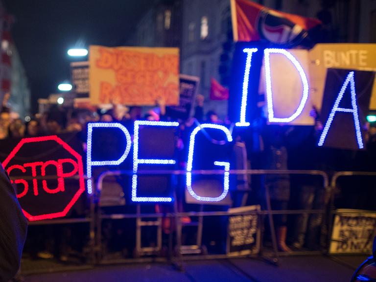 Gegner der Anti-Islam-Bewegung "Dügida" demonstrieren am 12.01.2015 in Düsseldorf (Nordrhein-Westfalen) mit einer Leuchtschrift "Stop PEGIDA"