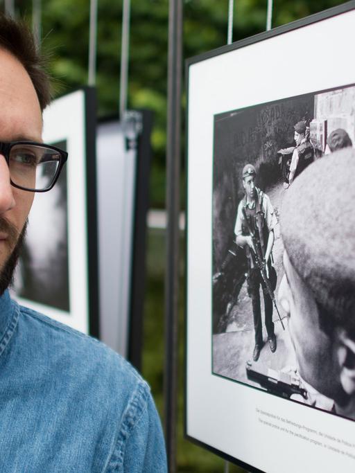 Der Fotograf Felix Kleymann steht am 17.06.2014 beim "4. Lumix Festival für jungen Fotojournalismus" an der Fachhochschule Hannover (Niedersachsen) neben einem Foto aus seiner Serie "Pacificacao", die sich mit einer Favela in Rio de Janeiro auseinandersetzt.
