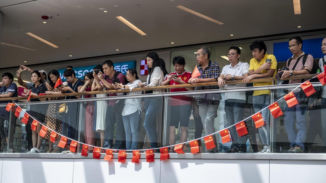 Pro-Peking Protestanten hinter chinesischen Flaggen in einer Mall in Hongkong. Zuvor hatte sich die Demokratiebewegung in Shopping-Centern zu spontanen Gesangseinlagen getroffen.
