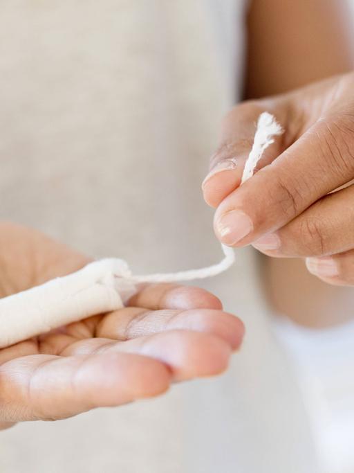 Eine Frau hält einen Tampon in der Hand.