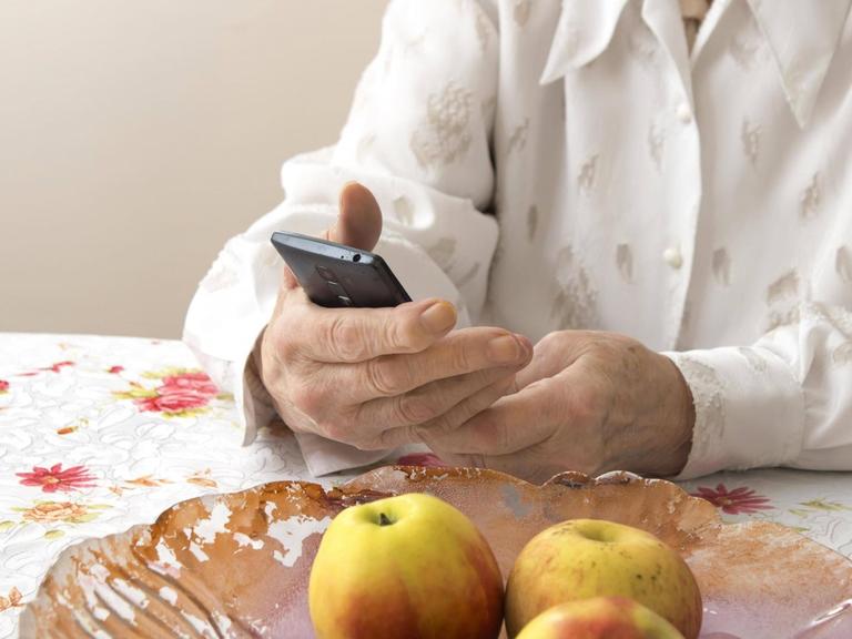 Die Hände einer älteren Frau halten ein Mobiltelefon. (Symbolfoto)