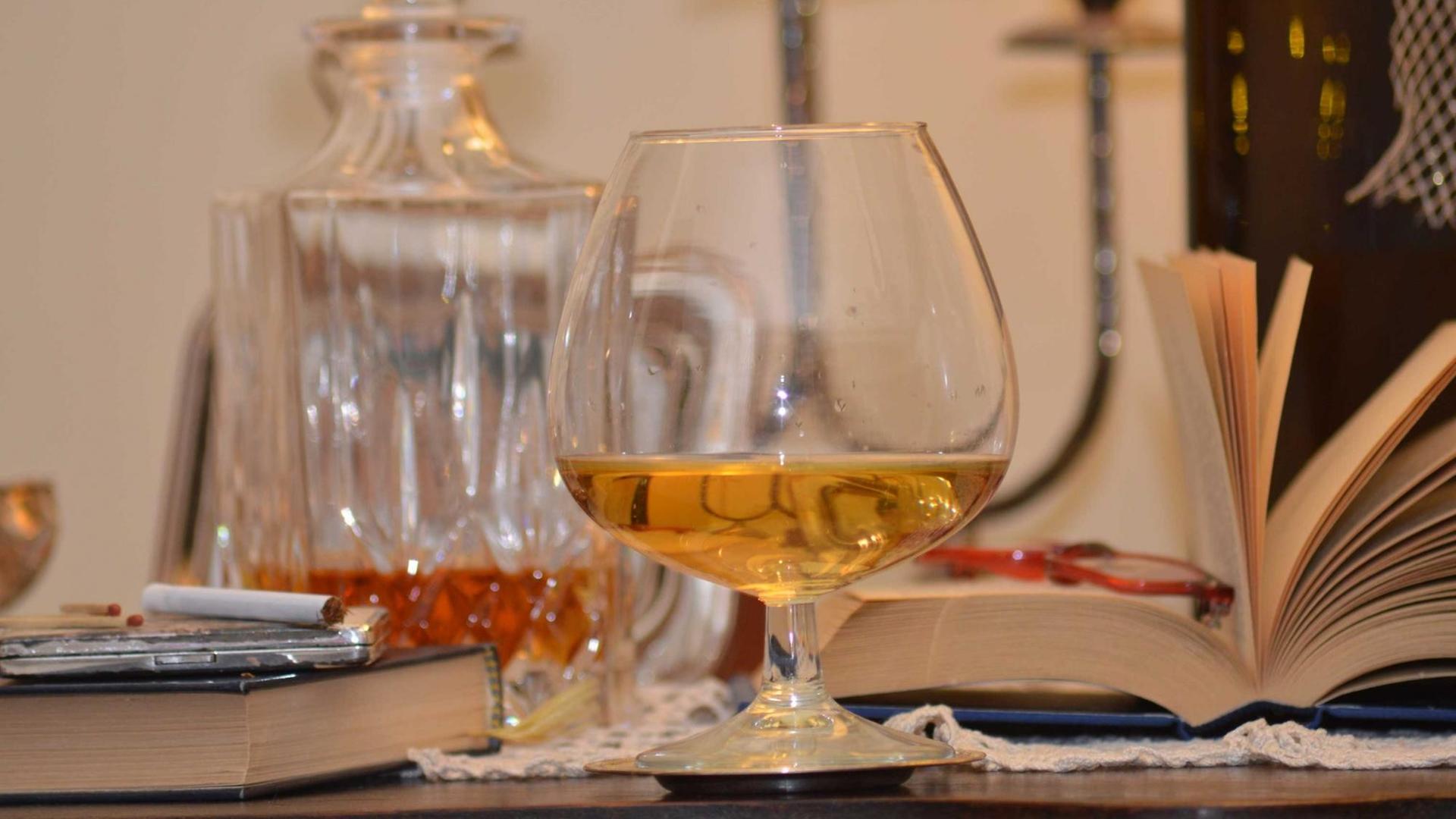 Cognac, ein Buch und Zigaretten auf einem Tisch