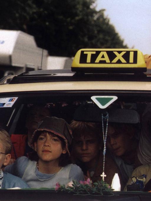 Eine Szene aus dem Kinofilm "Emil und die Detektive": Sechs Kinder in einem Taxi, einer guckt oben raus, sie suchen etwas.