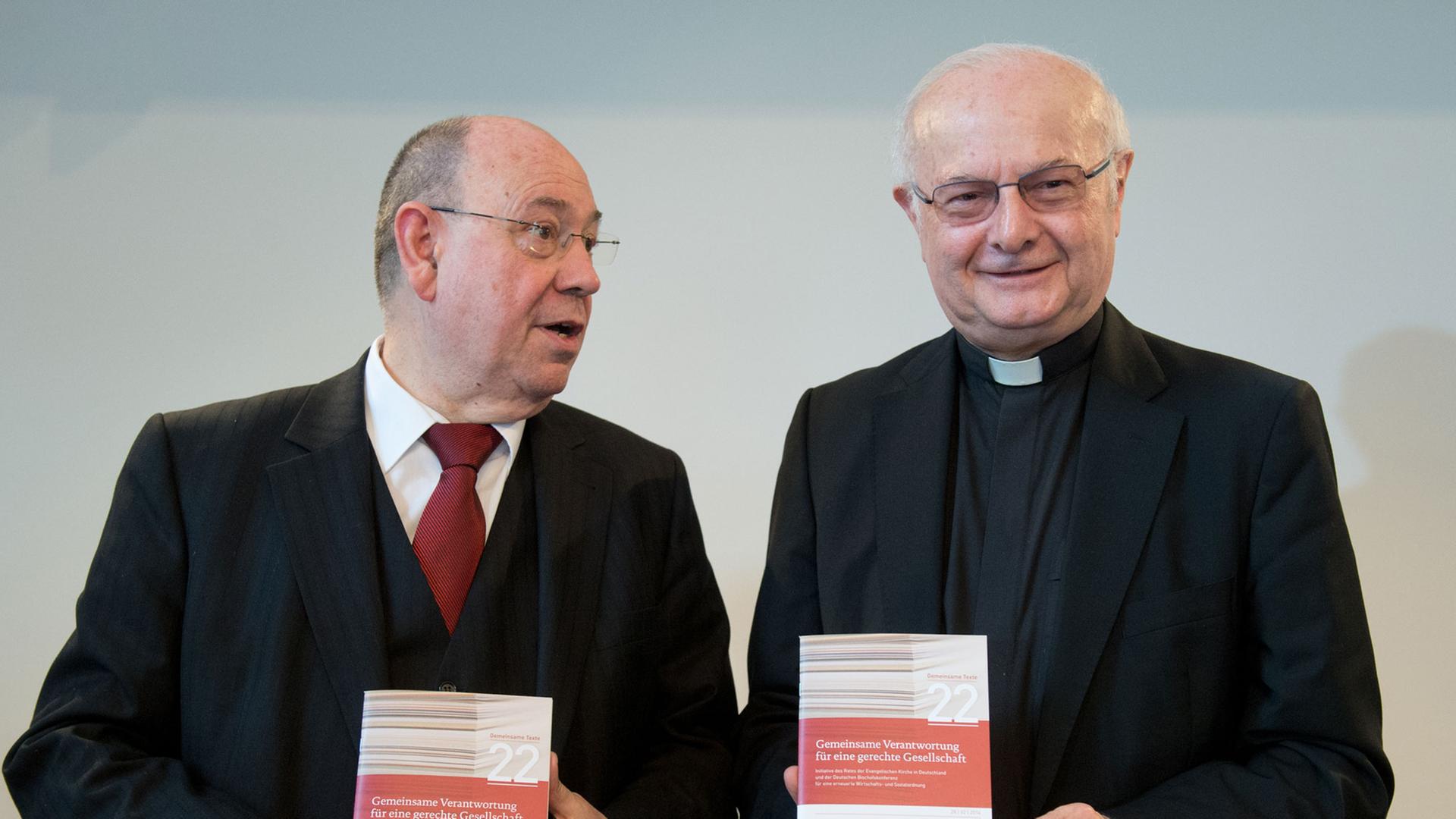 Erzbischof Robert Zollitsch (r), damals Vorsitzender der Deutschen Bischofskonferenz und der Vorsitzende der EKD in Deutschland, Nikolaus Schneider stellen im Febraur 2014 einen Entwurf der ökumenischen Sozialinitiative vor.