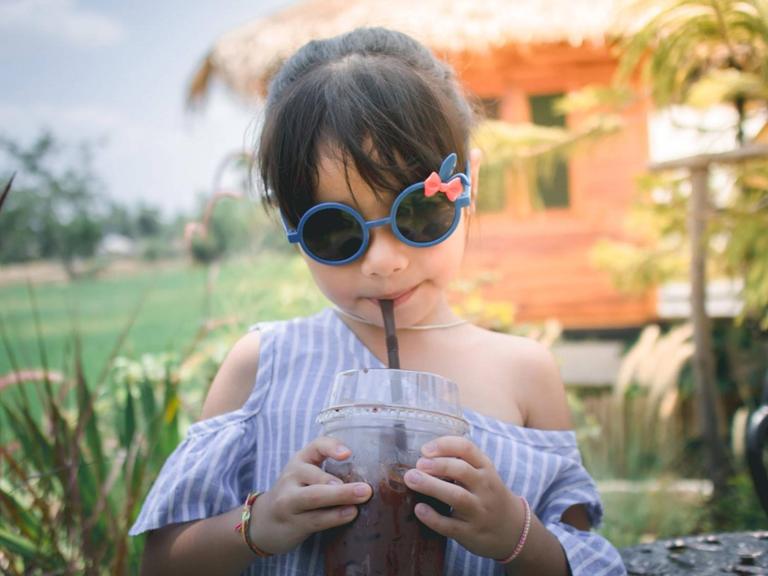 ein junges Mädchen mit Drink und Sonnenbrille auf einem Anwesen