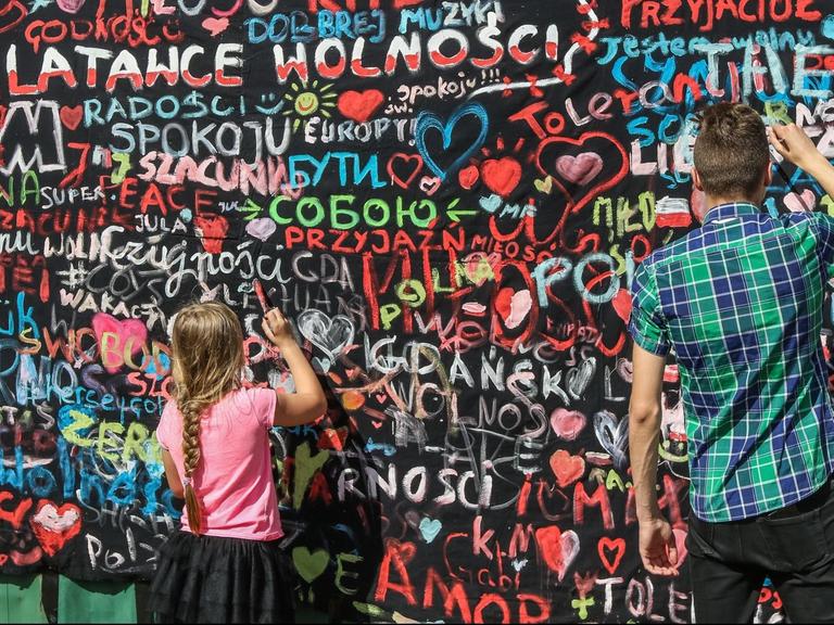 Menschen malen eine Mauer auf der Danziger Werft im Rahmen der "Freiheits- und Solidaritätstage" an. Hier nahm vor 30 Jahren die friedliche Revolution ihren Anfang.