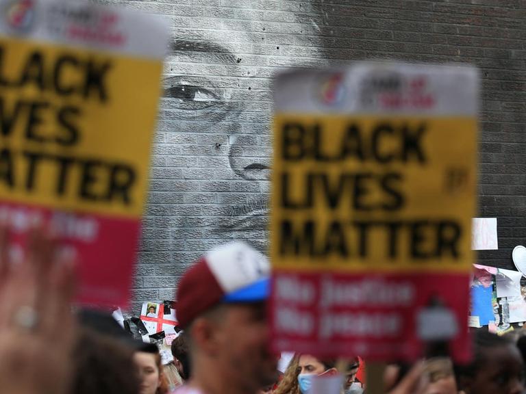 "Black-Lives-Matter"-Plakate werden vor dem Wandbild Marcus Rashfords in die Höhe gehalten.