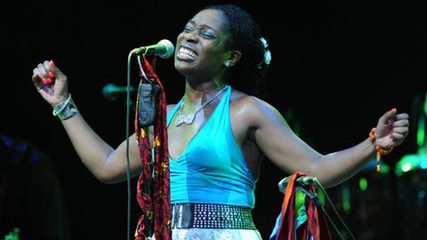 Die nigerianisch-amerikanische Musikerin Iyeoka singt bei einem Live-Konzert in Istanbul im August 2014 mit geschlossenen Augen und ausgebreiteten Armen in ein Mikrofon.