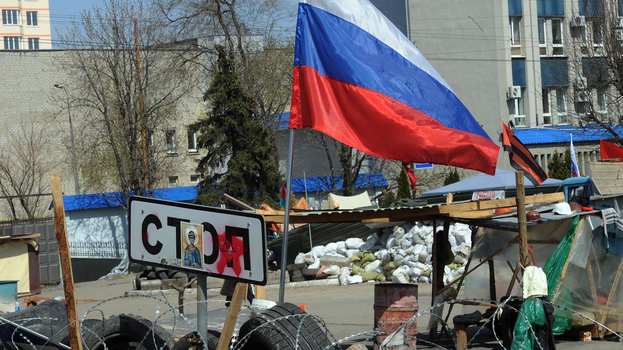 Barrikade aus Autoreifen, darauf ein Stop-Schild und eine russische Fahne.