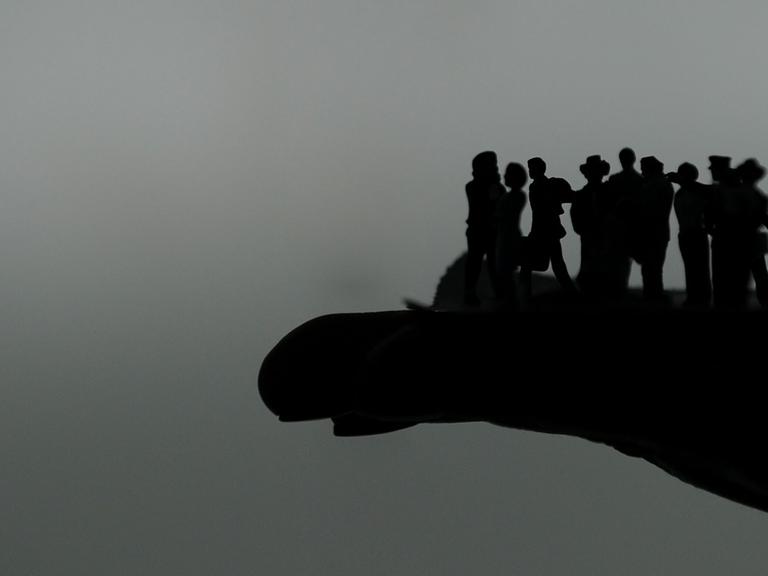 Die Silhouetten von Figuren auf einer Hand.