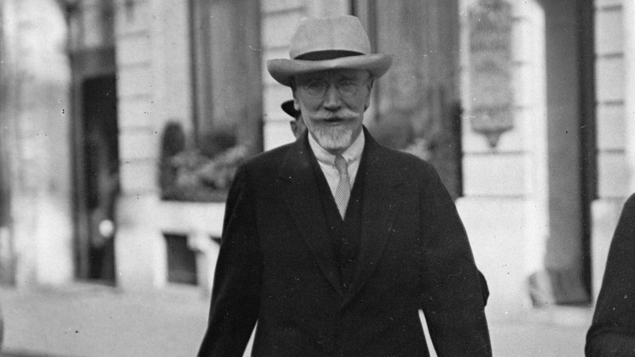 Eleftherios Venizelos trägt Hut, Bart und einen Anzug und läuft auf einer Straße. (Historische schwarzweiß Fotografie)