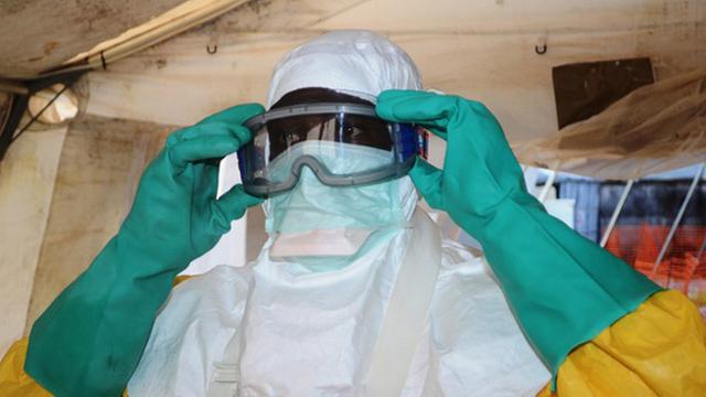 Ein Arzt hat Schutzanzug, Handschuhe und Gesichtsmaske angelegt, um vor infektiösem Material geschützt zu sein.