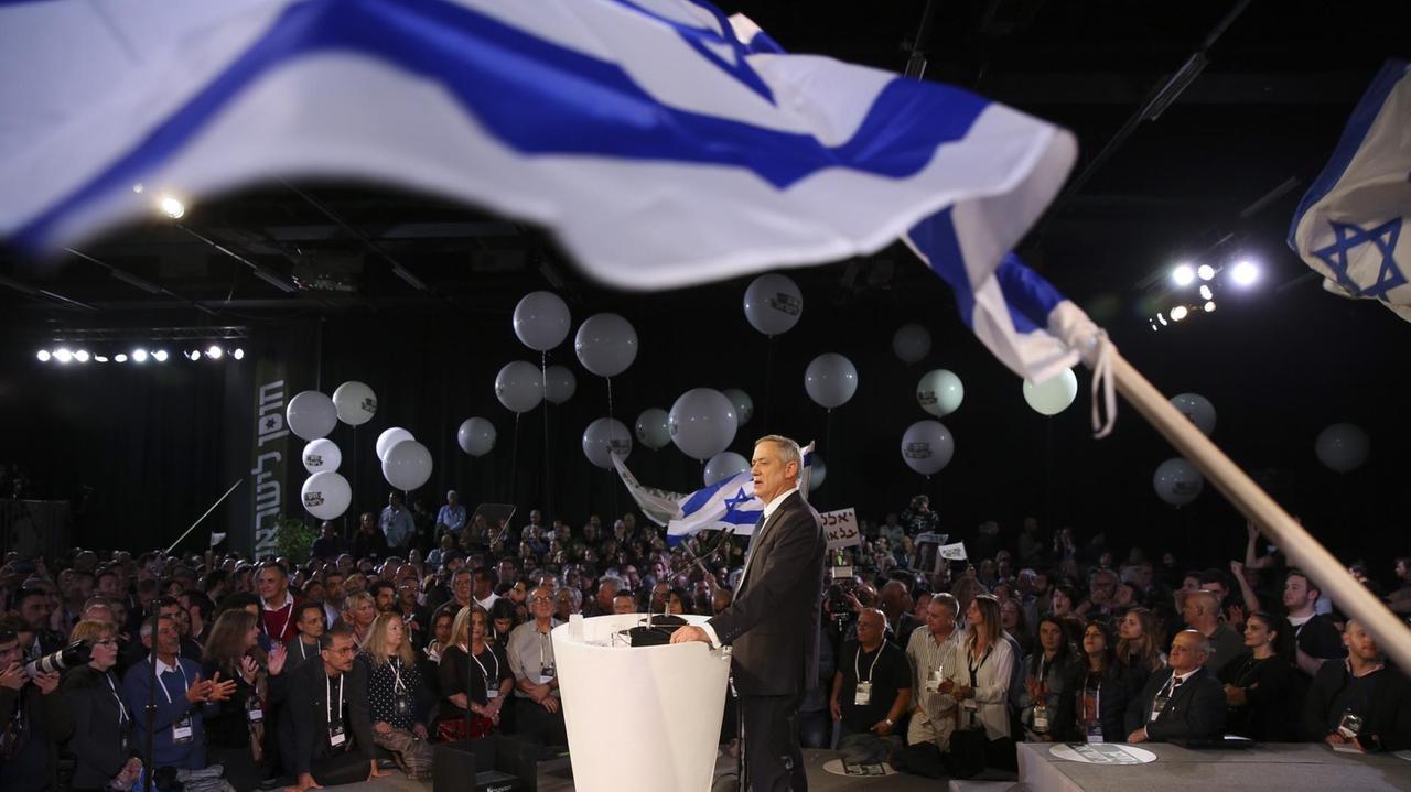 Der ehemalige Militärchef und heutige Oppositionspolitiker Benny Gantz steht bei einem Wahlkampfauftritt in Tel Aviv am Rednerpult. Zu sehen sind israelische Flaggen, Zuschauer und weiße Luftballons.