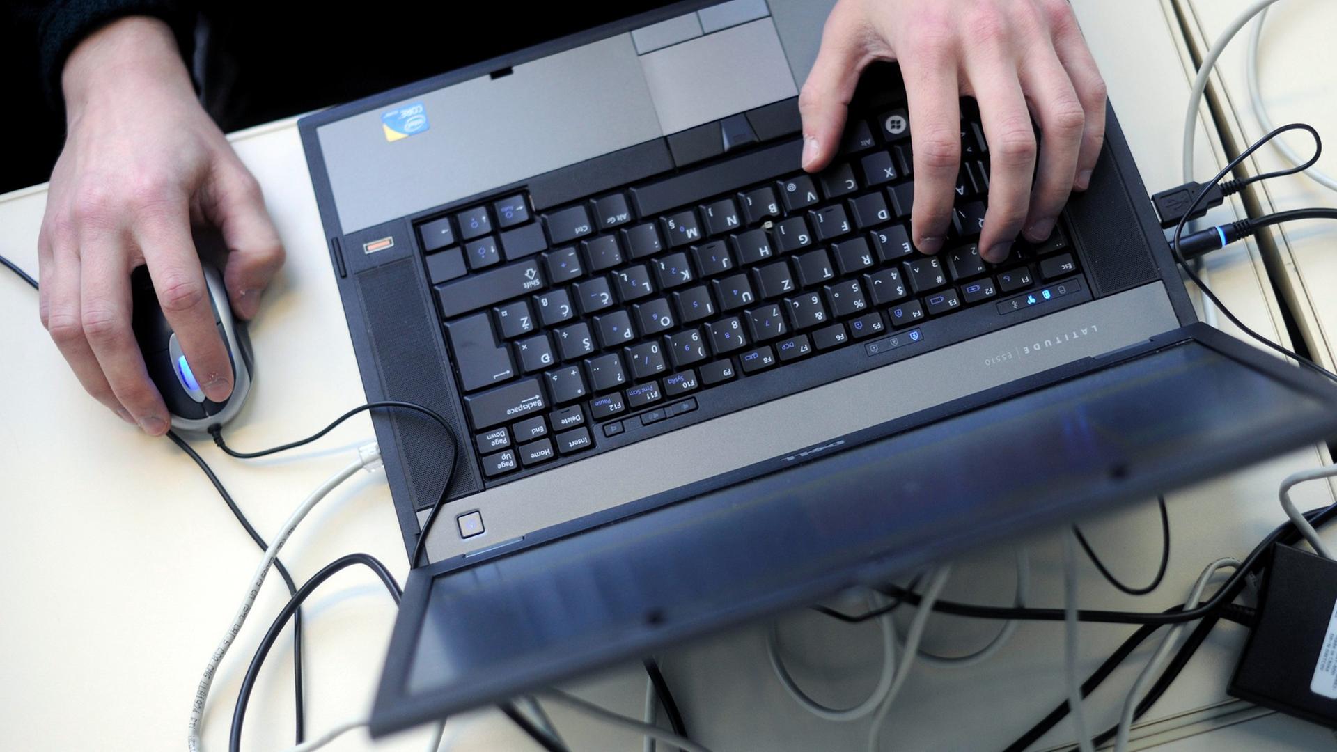 Eine Person bedient einen Laptop mit einer Mouse.