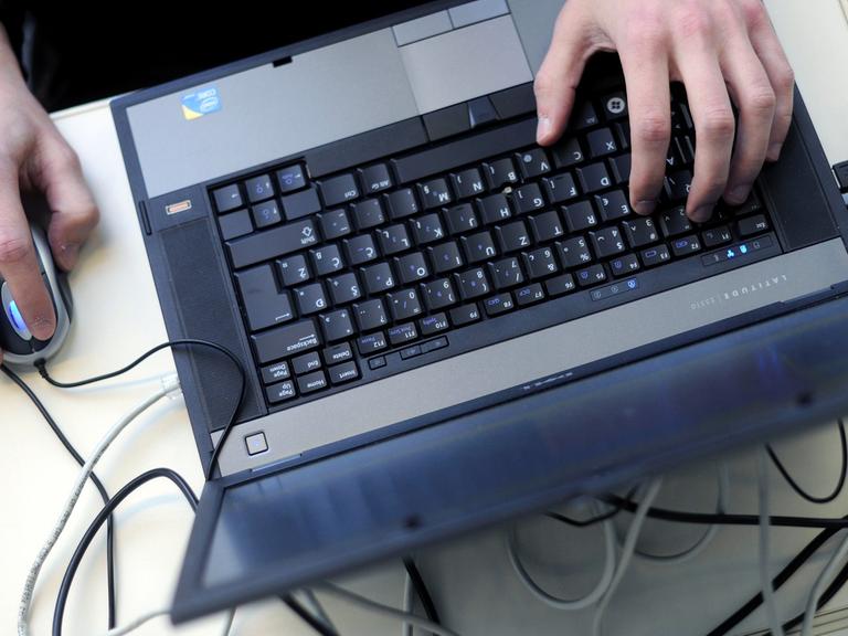 Eine Person bedient einen Laptop mit einer Mouse.