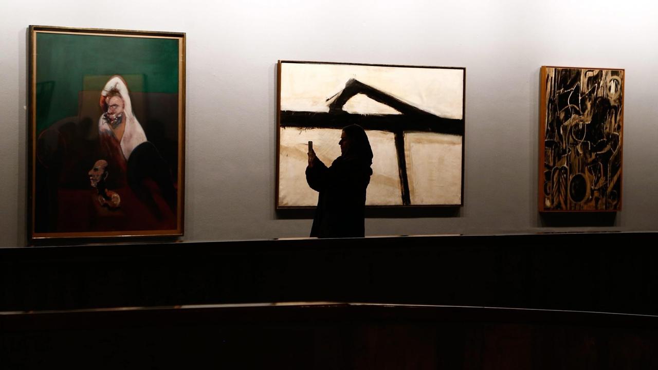 Die Silhouette einer Frau vor drei modernen Kunstwerken im "Tehran Museum of Contemporary Art"