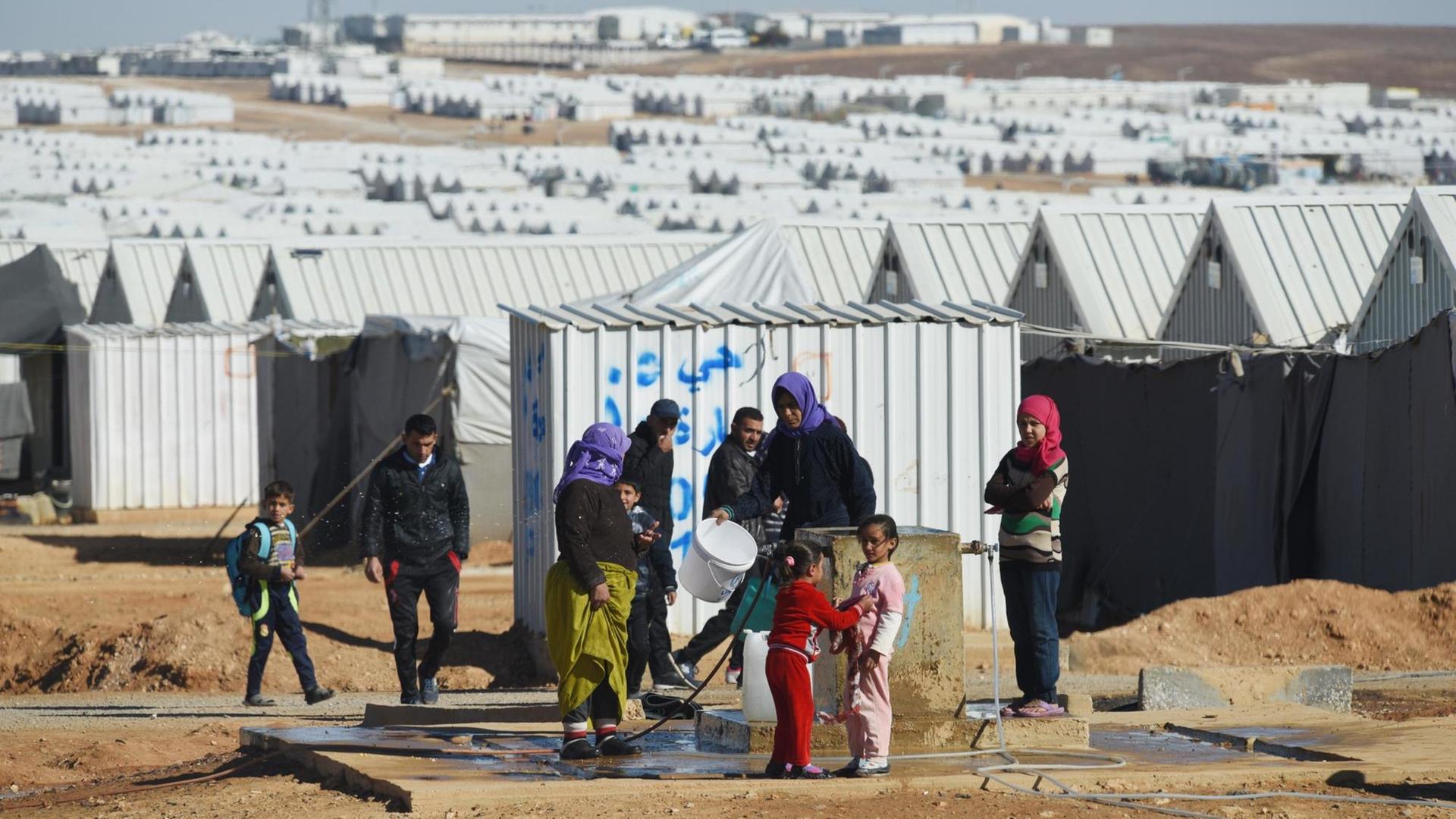 Frauen und Kinder vor den Hütten des UNHCR.Flüchtlingslagers in Azraq in Jordanien.