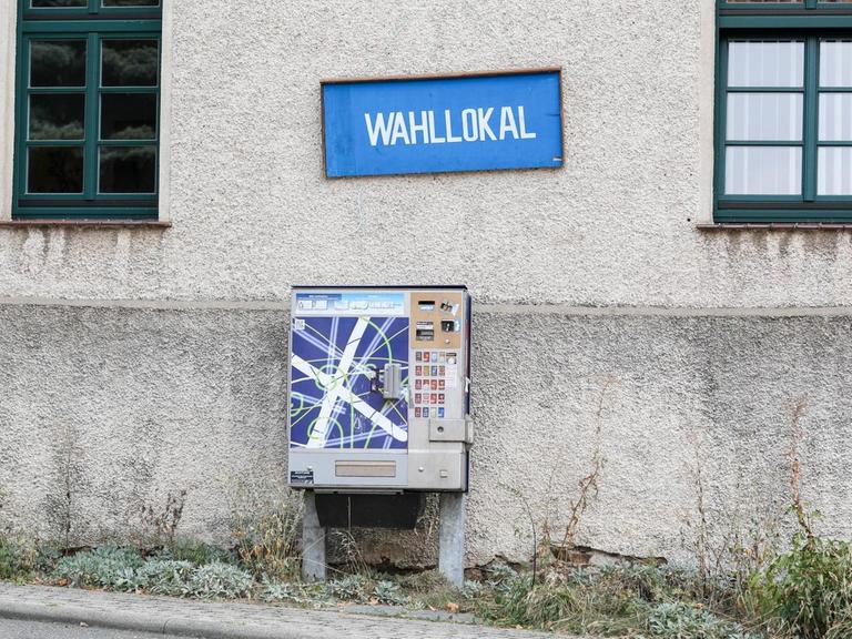 In dem sächsischen Ort Cannewitz hängt an einer Hauswand ein blaues Schild mit der weißen Aufschrift "Wahllokal". Darunter ist ein Zigarettenautomat.