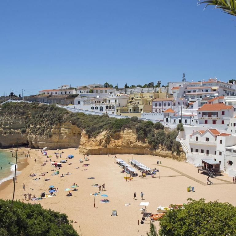 Blick auf den Strand Praia de Carvoeiro an der Algave in Portugal. Im Hintergrund sind zahlreiche nah am Strand liegenden Hotels zu sehen.