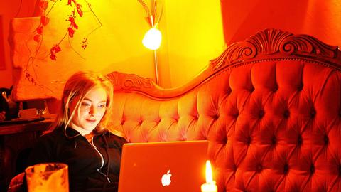 Eine Frau surft an ihrem Laptop in einem Berliner Internet-Café - und lächelt.