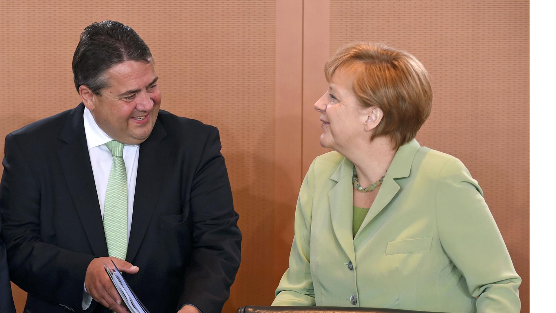 Die Kanzlerin unterhält sich am 18.06.2014 zu Beginn der Kabinettssitzung mit Wirtschaftsminister Gabriel. Beide lachen.