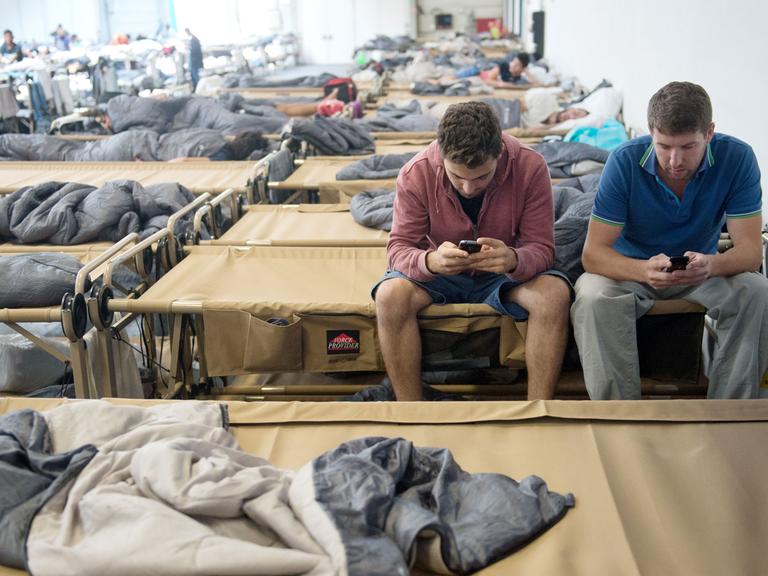 Zwei Flüchtlinge in einer Notunterkunft in Stuttgart mit ihren Smartphones