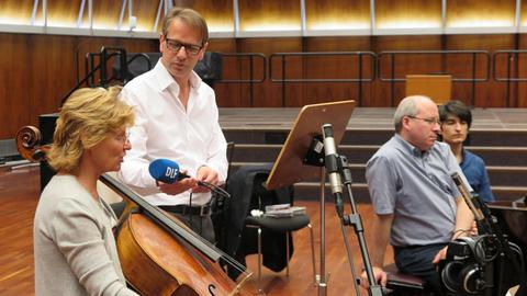 Deutschlandfunkredakteur Christoph Schmitz interviewt die Cellistin Maria Kliegel am Instrument, im Hintergrund ist Oliver Triendl am Flügel zu sehen.