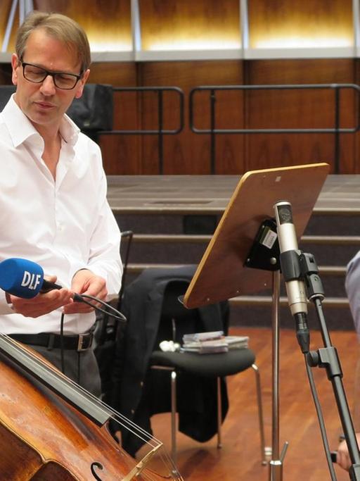 Deutschlandfunkredakteur Christoph Schmitz interviewt die Cellistin Maria Kliegel am Instrument, im Hintergrund ist Oliver Triendl am Flügel zu sehen.