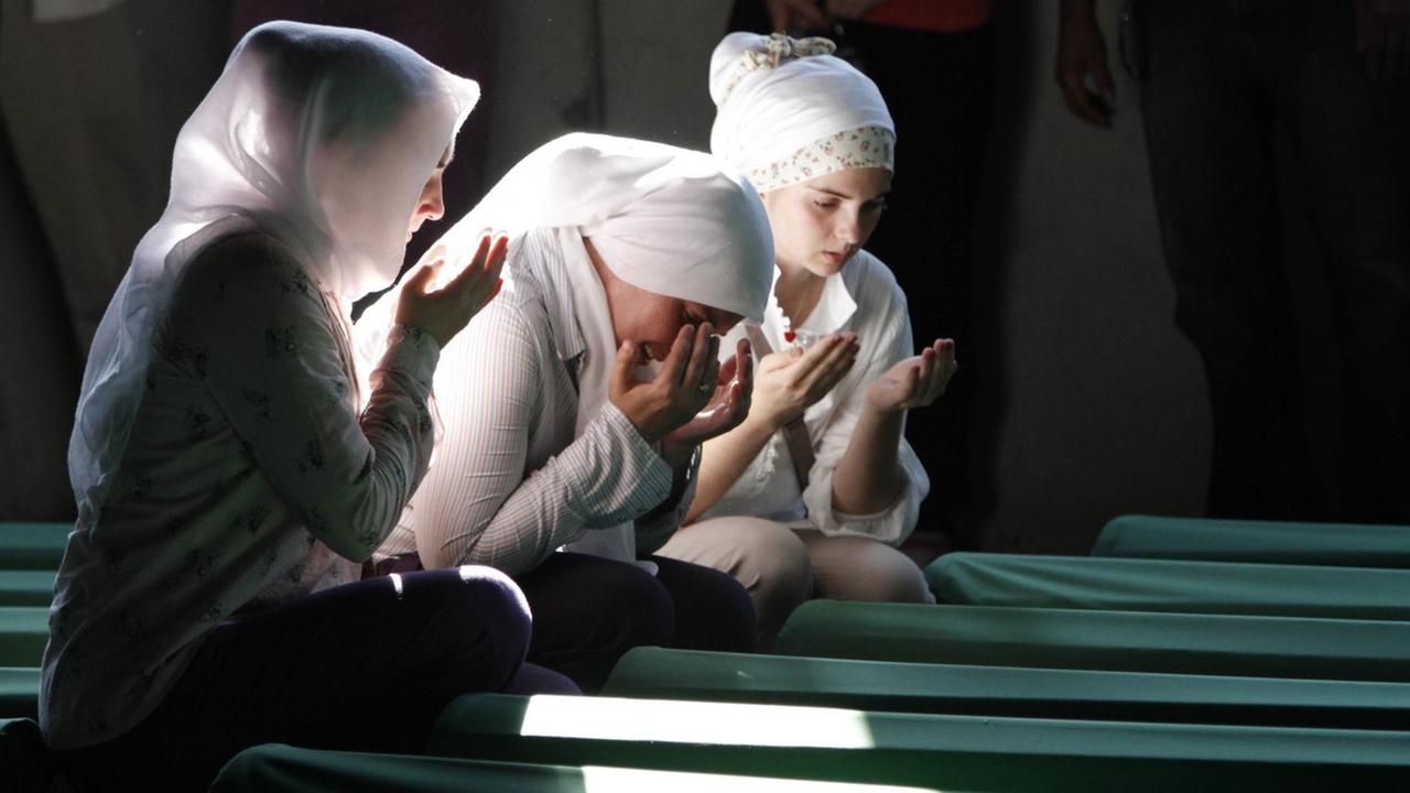 Bosnische Muslimas beten in Potocari (Bosnien) vor Särgen von Opfern des Massakers von Srebrenica die in einer Gedenkstätte aufgestellt wurden.