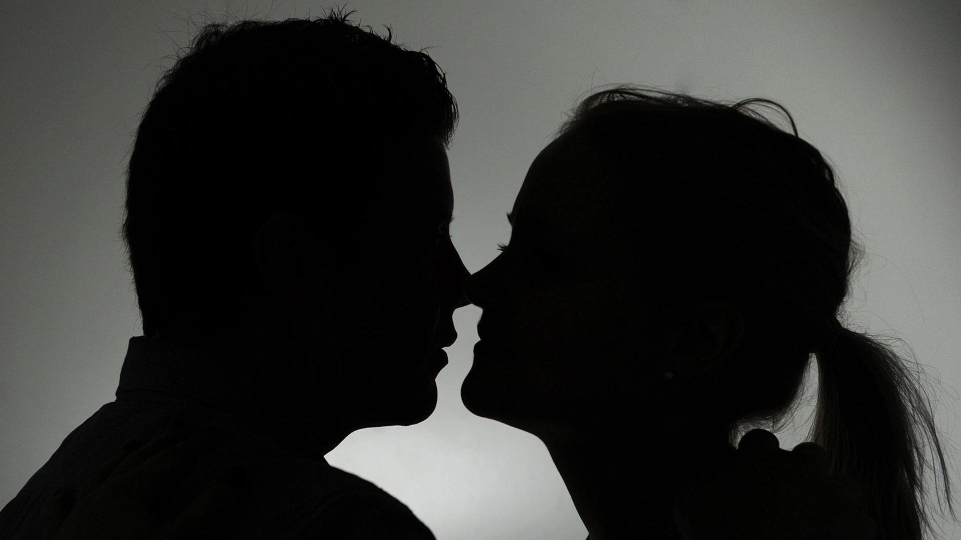 Ein Mann und eine Frau als Silhouette küssen sich. 