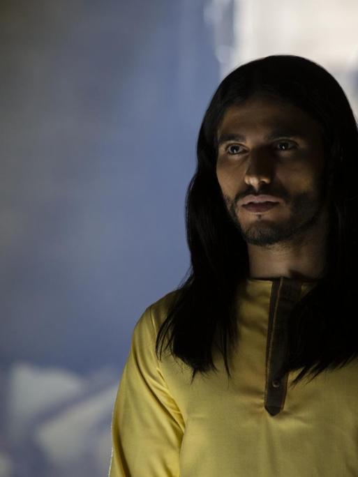 Eine Filmszene aus der Netflix Serie "Messiah" zeigt selbigen in gelbem Hemd, langer Mähne und Bart.